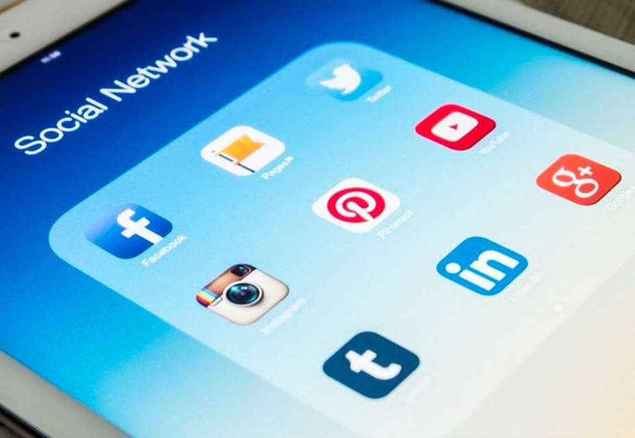 A tablet screen displays various social media app icons, including Facebook, Instagram, Twitter, YouTube, Pinterest, LinkedIn, Google+, and Tumblr, under a Social Network folder—ideal for content creation and digital advertising to boost brand awareness.