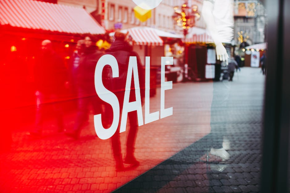 A shop window with a large SALE sign grabs attention. In the background, several people are walking on a bustling street with storefronts and red-striped awnings, illustrating effective branding for small businesses.